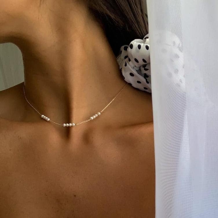 Stylish gold necklace with four station pearls, beautifully adorning a woman's neckline.