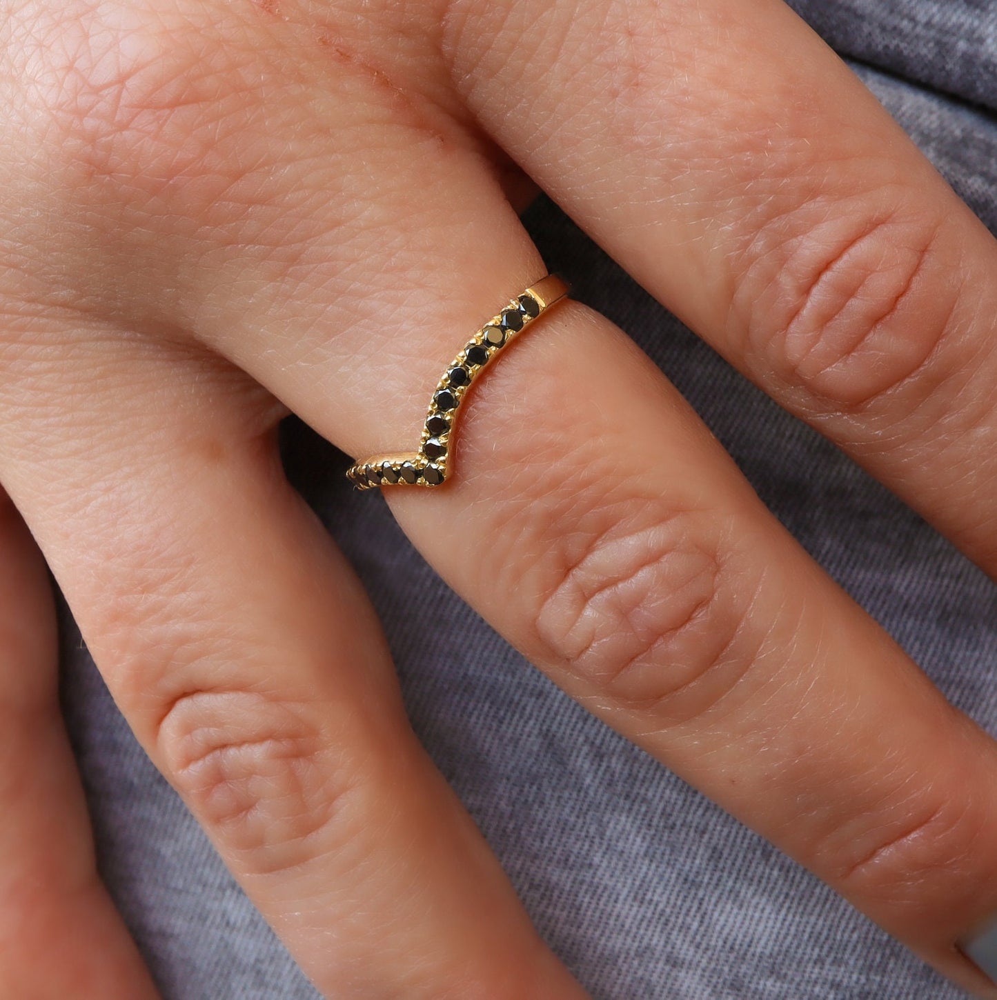טבעת בסגנון ייחודי, בצורת שפיץ משובצת יהלומים שחורים.