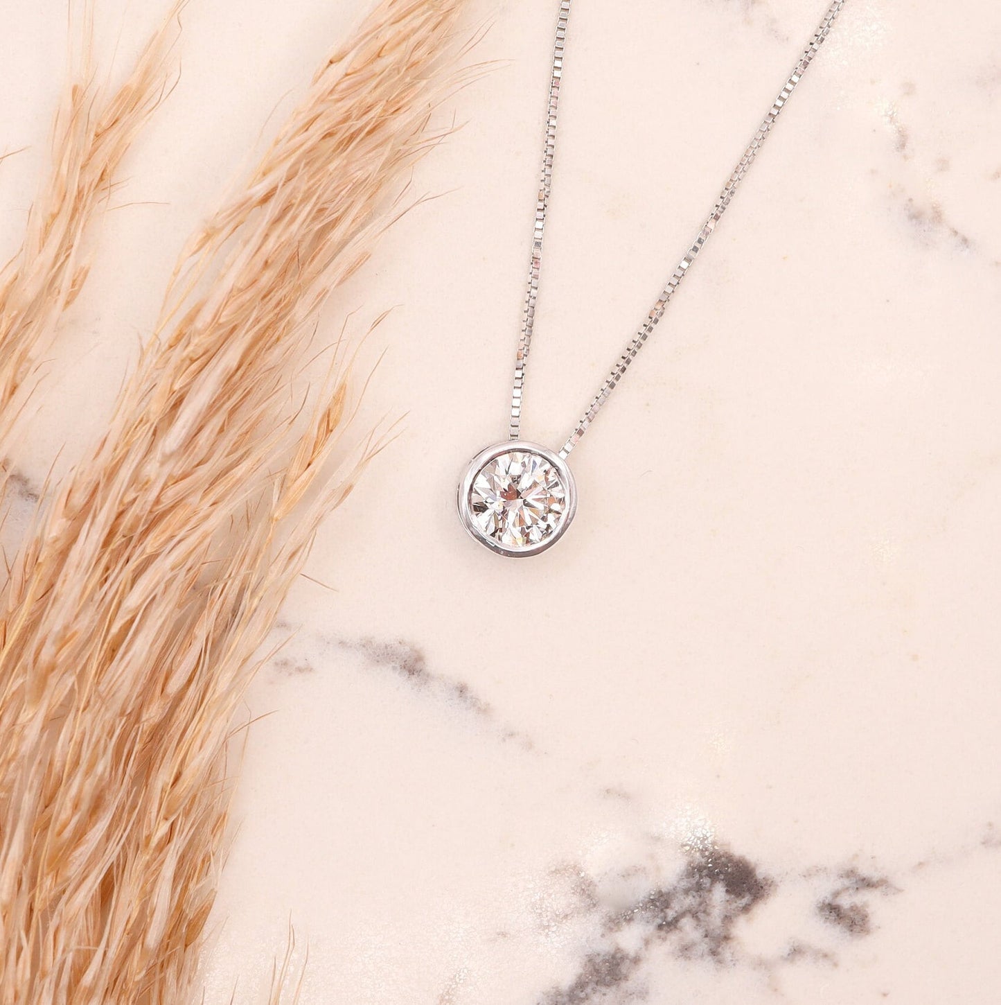 Floating Diamond White Gold Necklace in a bezel setting, elegantly presented on a marble slab