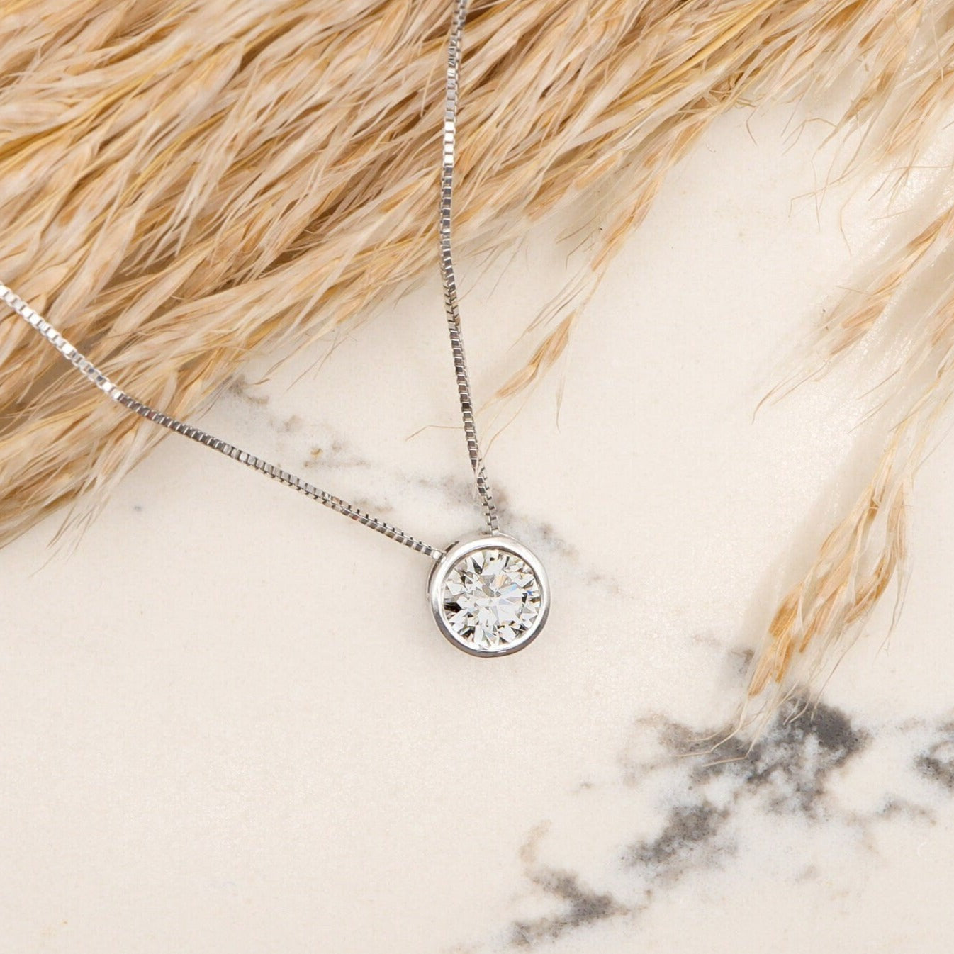 White Gold Floating Diamond Necklace with bezel setting, beautifully showcased on a marble slab