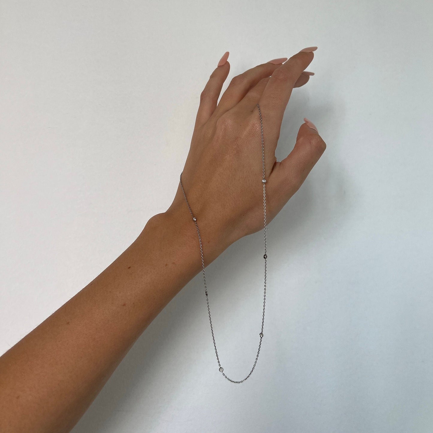 Woman holding diamond station necklace in her hand.