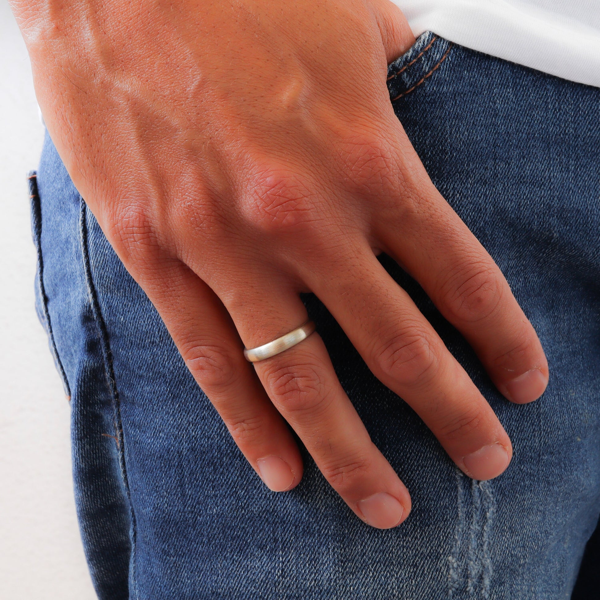 Stylish men's wedding ring in white gold, worn on a masculine hand.