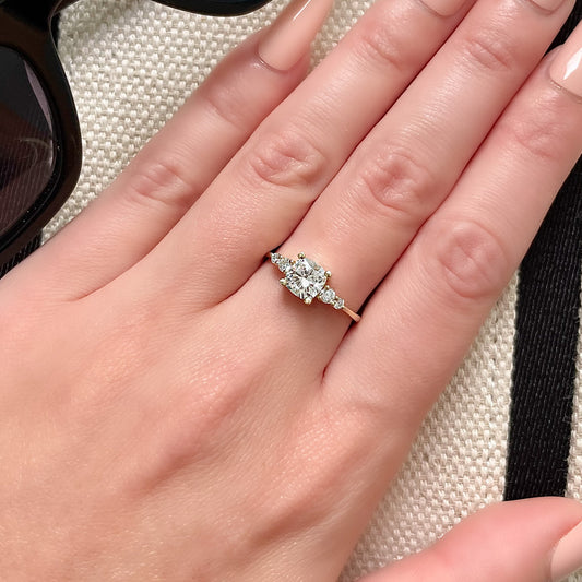 טבעת אירוסין זהב צהוב עם יהלום מרכזי בחיתוך קושן ויהלומי צד, נראית נקייה ומבריקה מאוד על יד של אישה לאחר ניקוי ביתי.