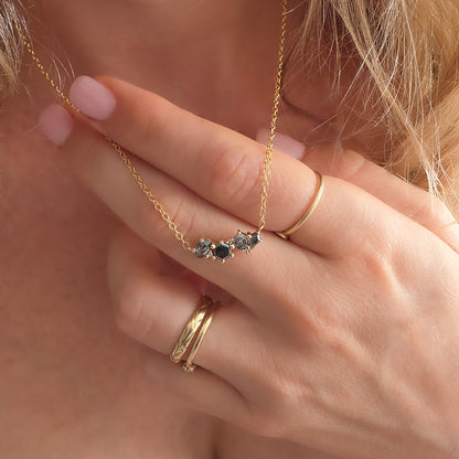 Hand holding the Galaxy Salt & Pepper Diamond pendant on a 14K yellow gold chain at the neckline – Dina Jewelry