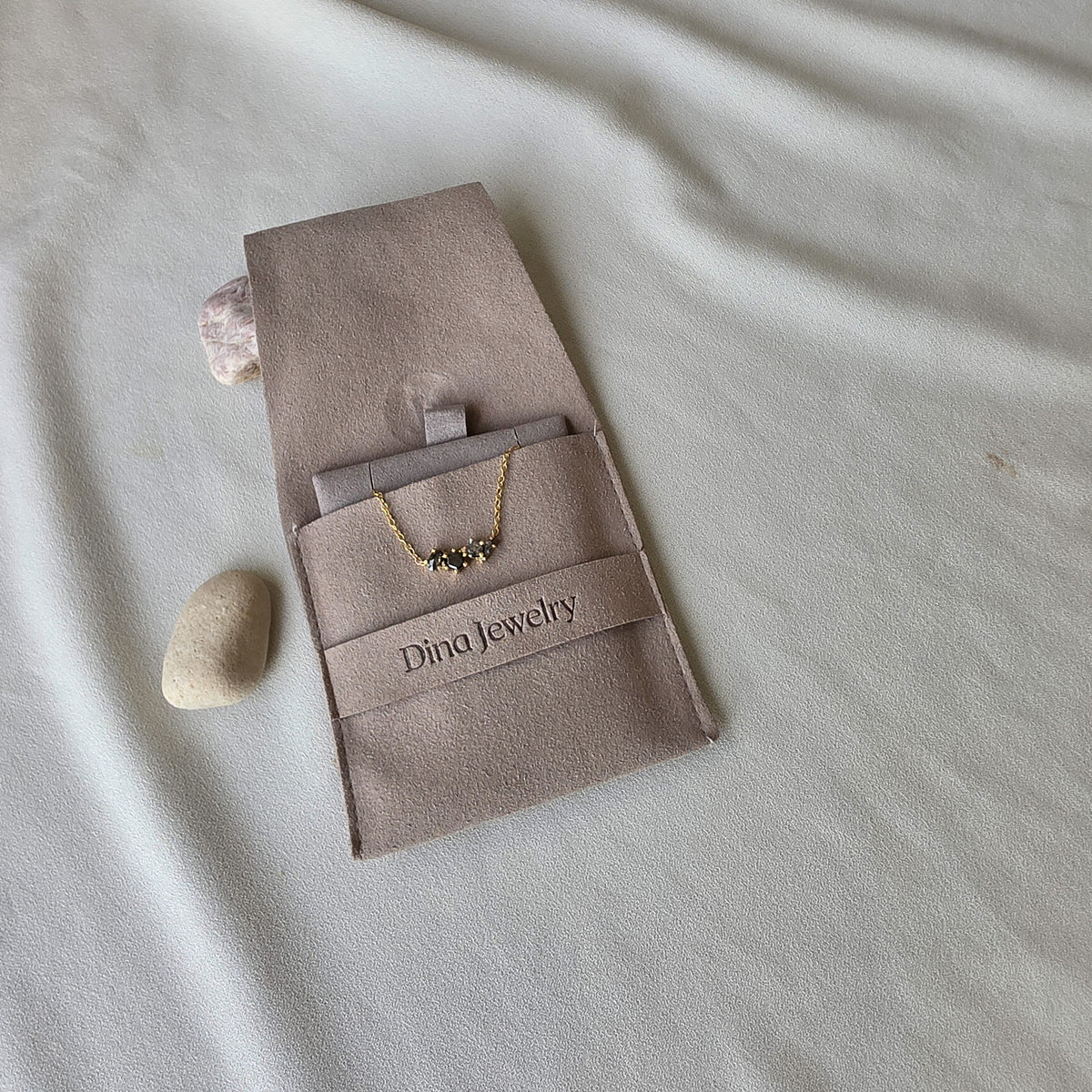 שרשרת יהלומים גלקסיה מונחת בשקית התכשיט של Dina Jewelry, זהב צהוב ויהלומי סולט אנד פפר טבעיים