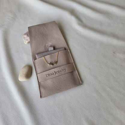 שרשרת יהלומים גלקסיה מונחת בשקית התכשיט של Dina Jewelry, זהב צהוב ויהלומי סולט אנד פפר טבעיים