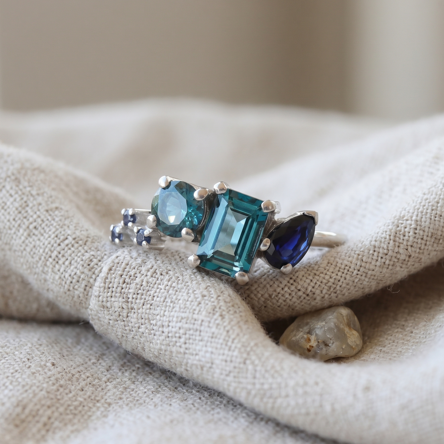 White gold gemstone ring featuring topaz and sapphire in an asymmetrical layout.