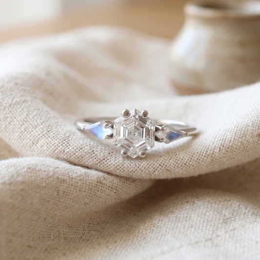 Engagement ring in white gold featuring hexagonal diamond with two moonstones kite shapes.