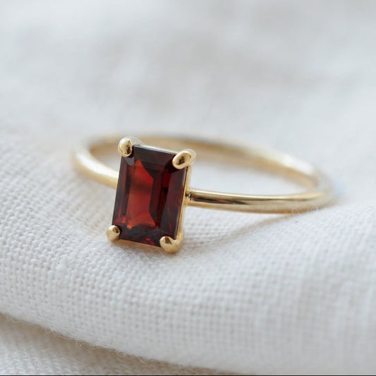 Solitaire ring in gold with a natural red garnet gemstone.