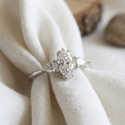 Three stone engagement ring featuring marquise and two pear diamond in white gold.