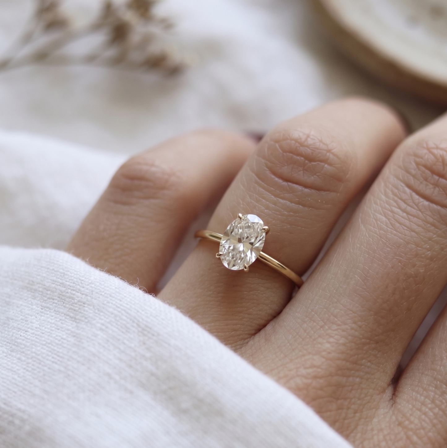 Classic oval design in yellow gold engagement ring on a woman's finger.