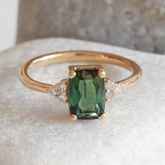 Green tourmaline in a cushion cut on a solid gold solitaire ring with diamonds.