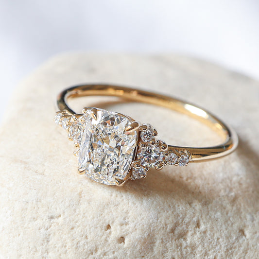 Elegant engagement ring featuring an elongated cushion-cut natural diamond with round side diamonds, set in 14k gold.