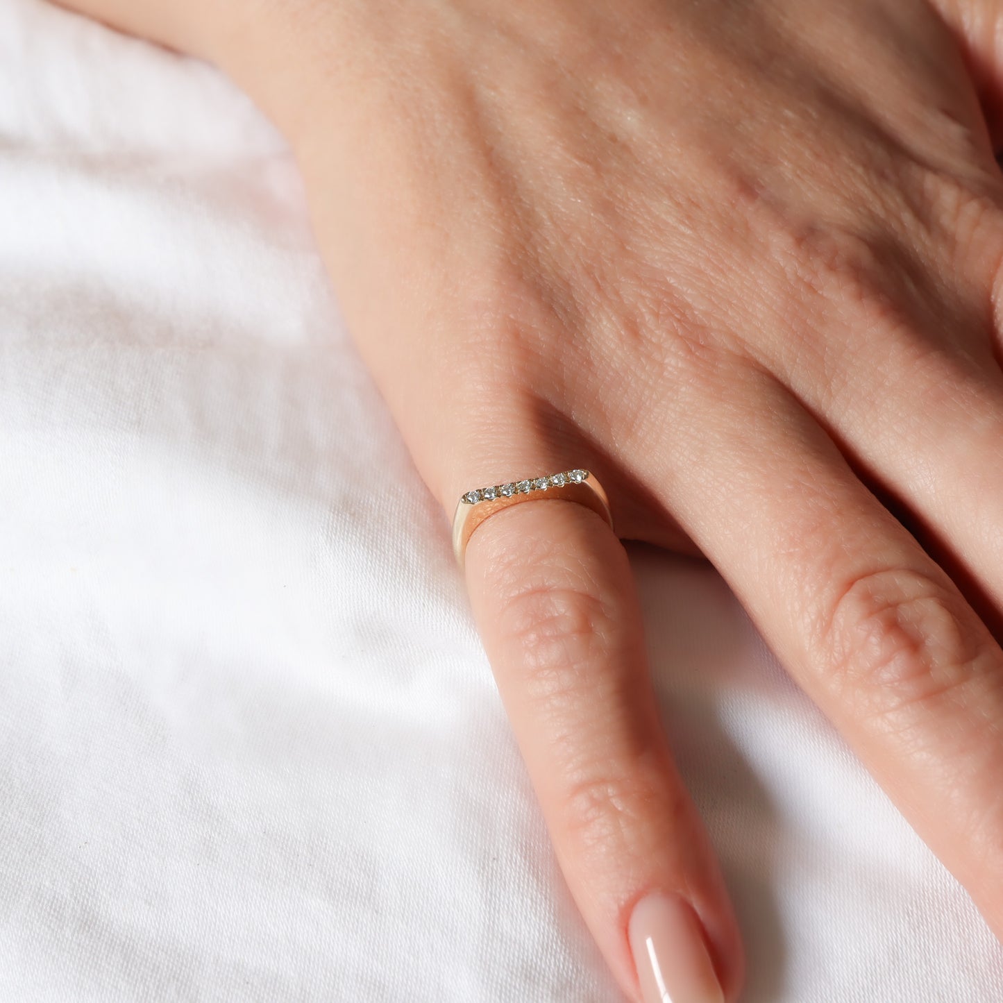 טבעת זהב 14 קראט בעלת פרופיל שטוח משובצת שורת יהלומים לבנים על אצבע.