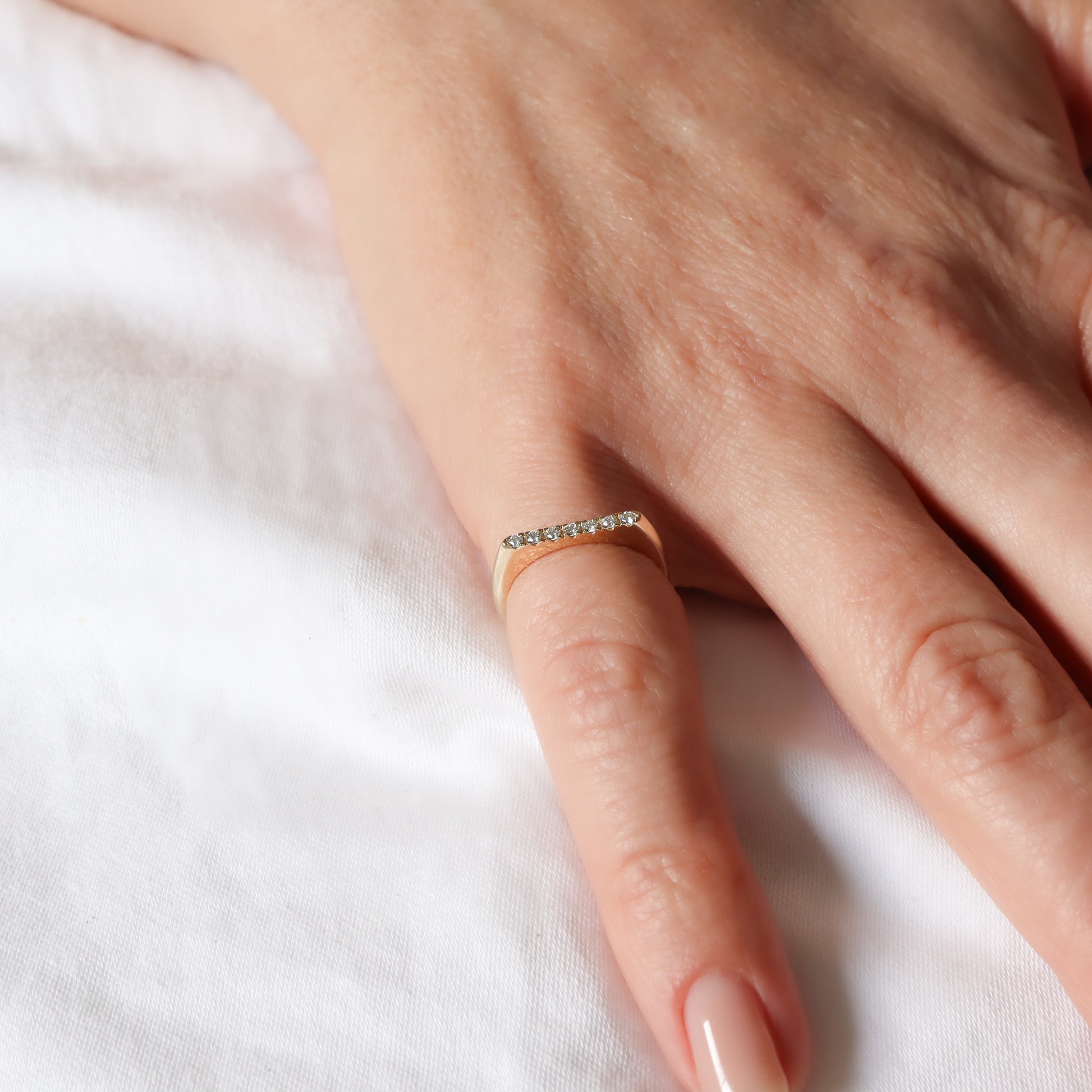 טבעת זהב 14 קראט בעלת פרופיל שטוח משובצת שורת יהלומים לבנים על אצבע.