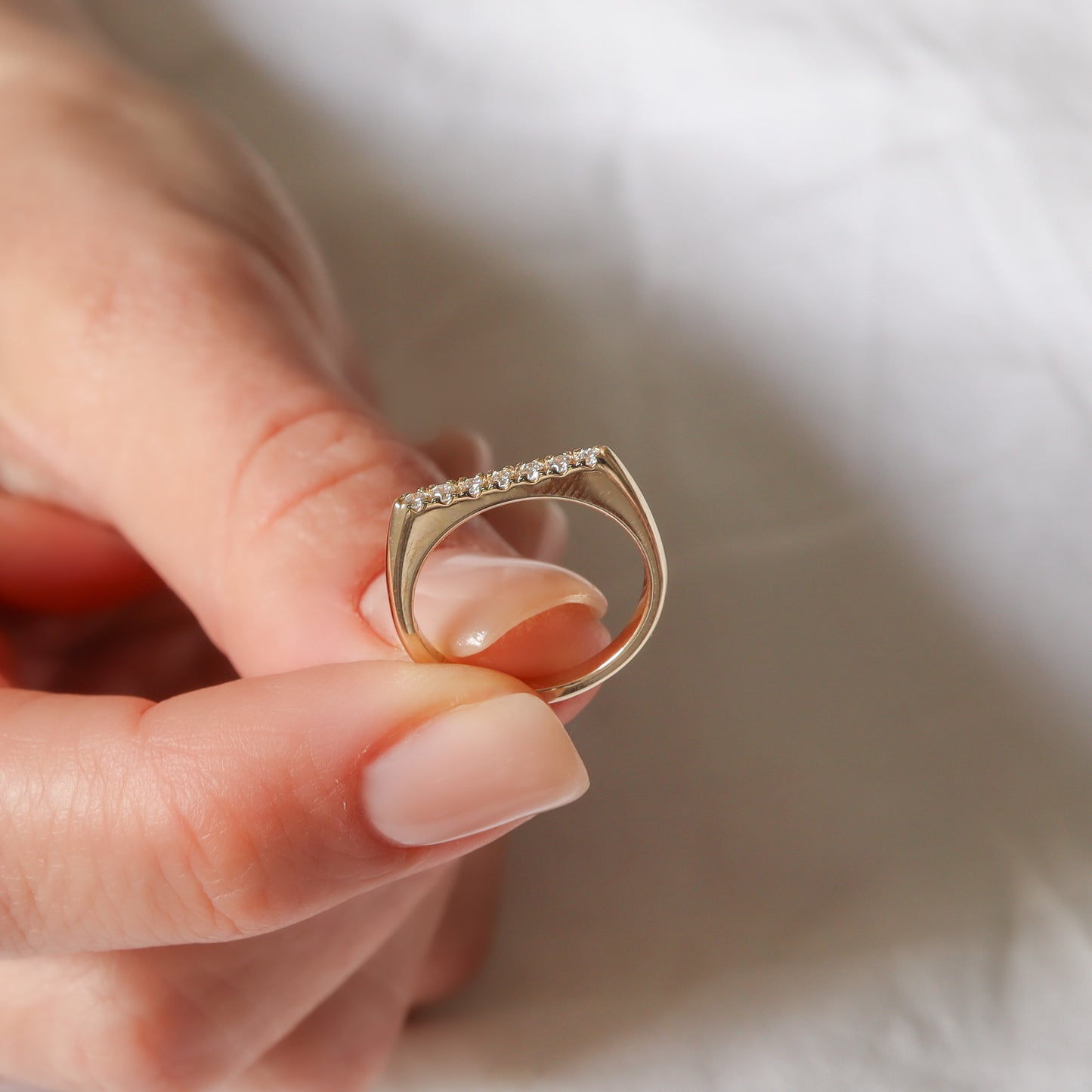 טבעת יהלומים בזהב צהוב בצורה מיוחדת עם חלק עליון שטוח ובומשובצים יהלומים לבנים.