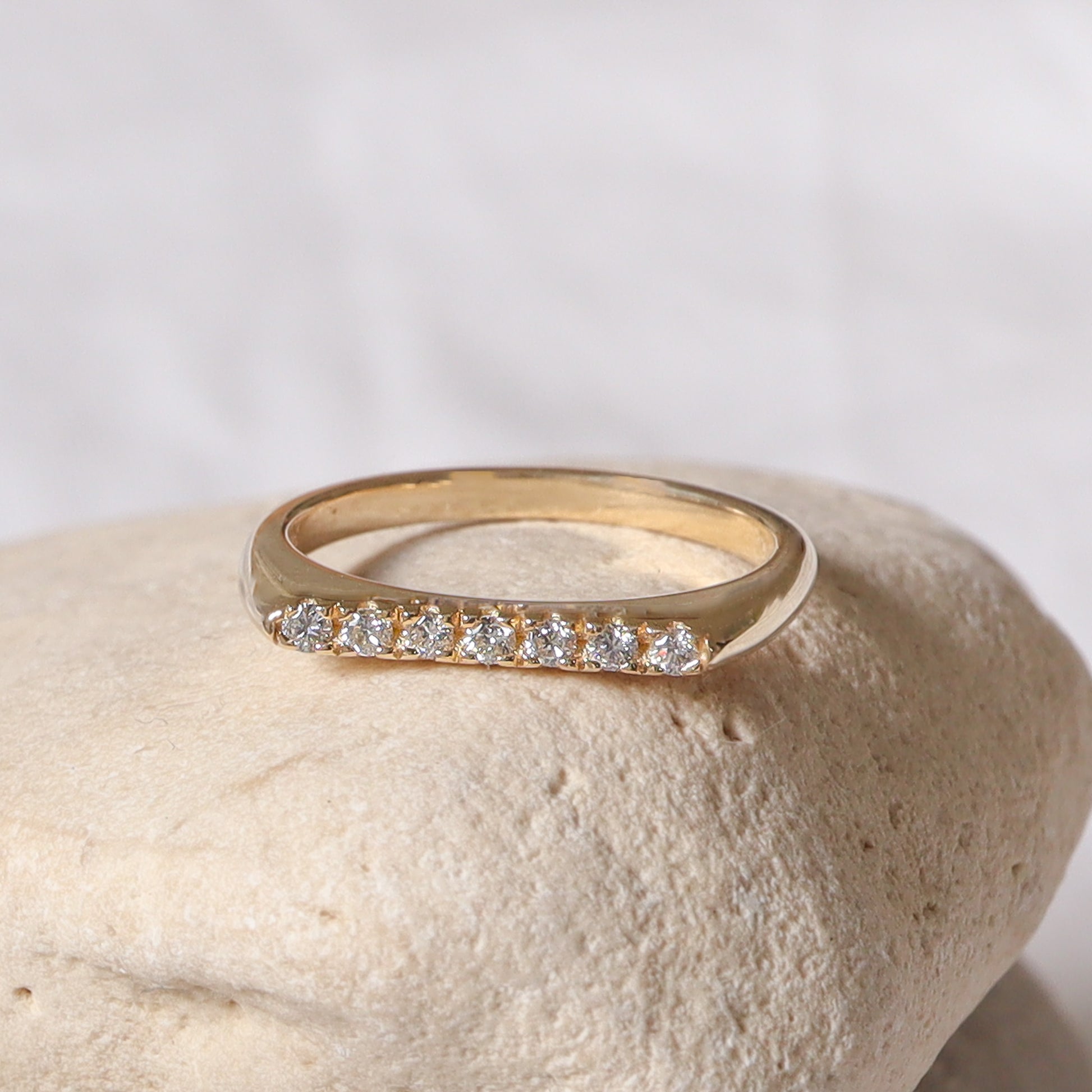 צילום מקרוב של הפרופיל הגיאומטרי השטוח של הטבעת המציג את איכות שיבוץ היהלומים בזהב.