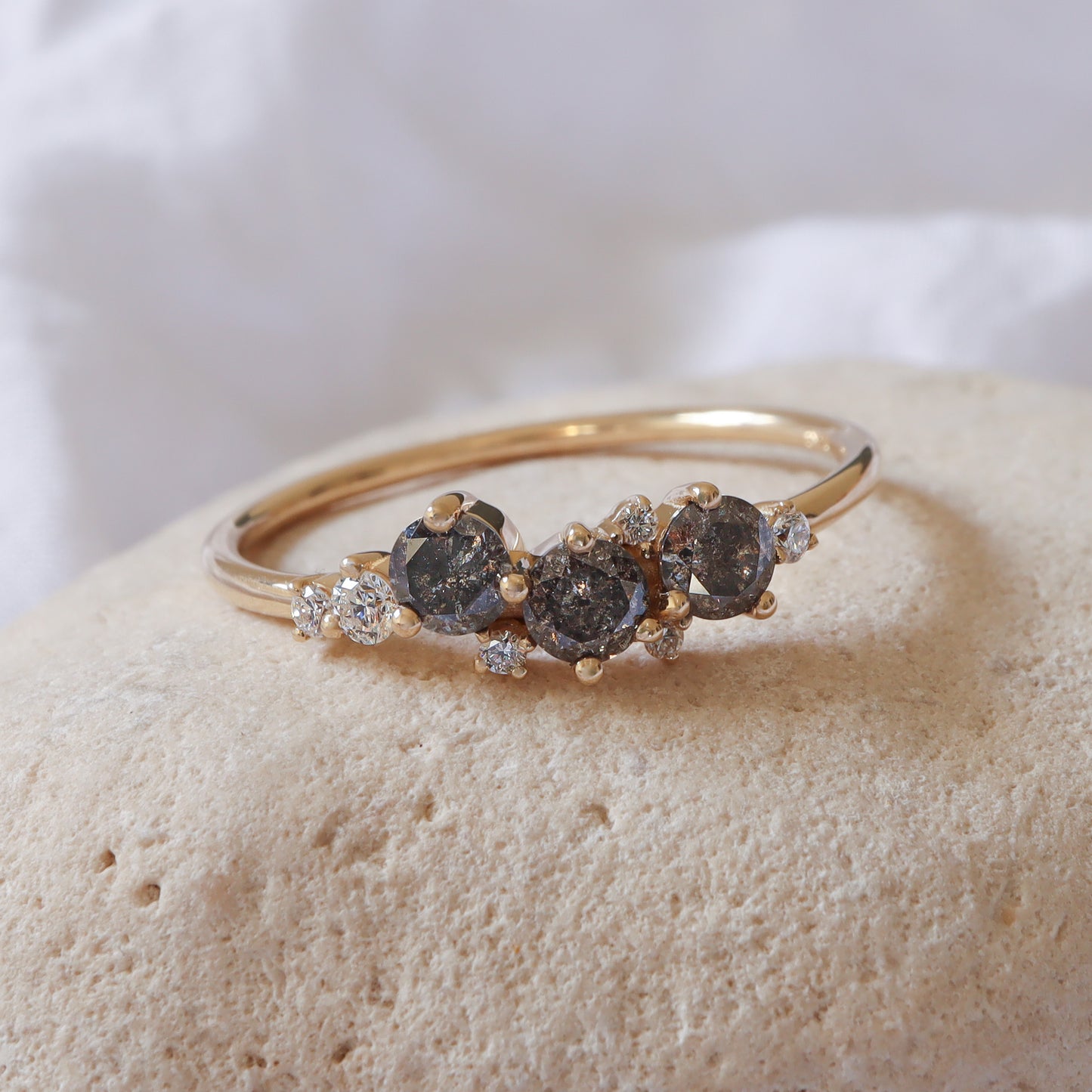 טבעת זהב צהוב 14 קראט עם מקבץ יהלומי מלח-פלפל אפורים ויהלומים לבנים משובצים יחד במרכז במבנה קלאסטר.