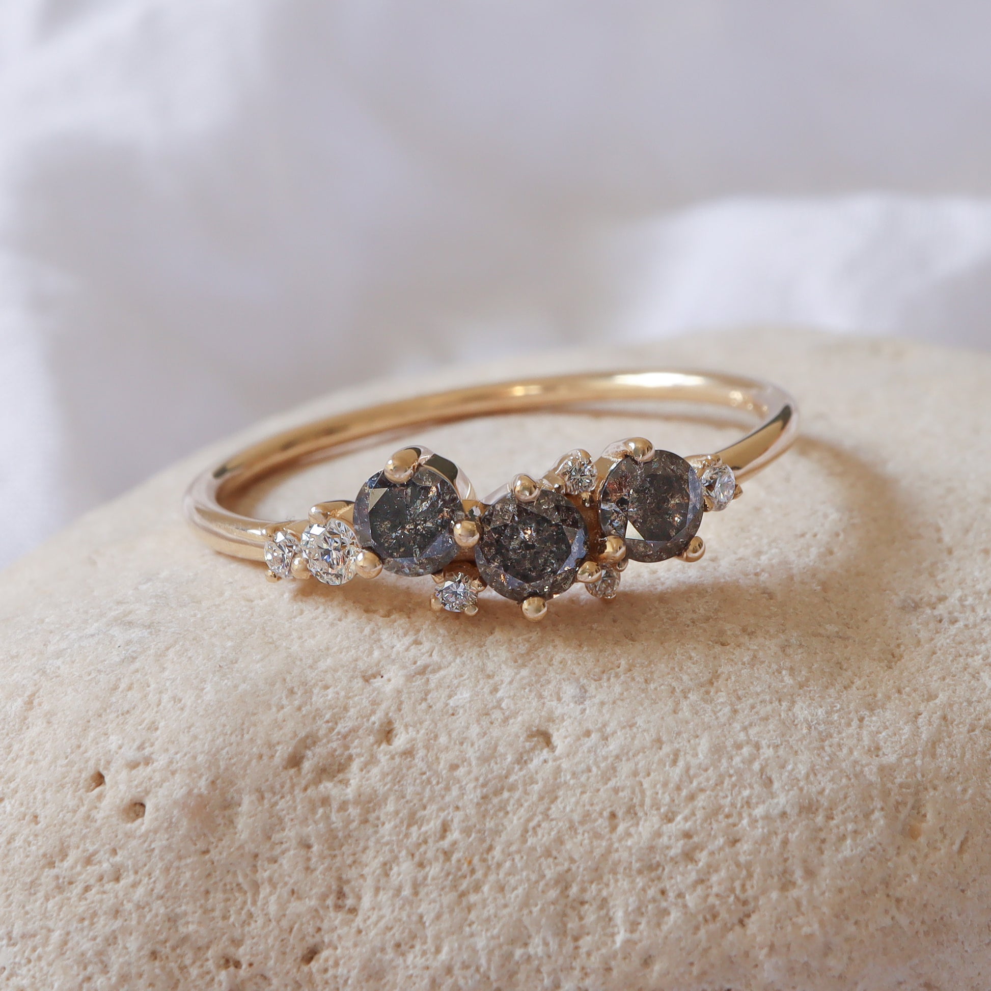 טבעת זהב צהוב 14 קראט עם מקבץ יהלומי מלח-פלפל אפורים ויהלומים לבנים משובצים יחד במרכז במבנה קלאסטר.