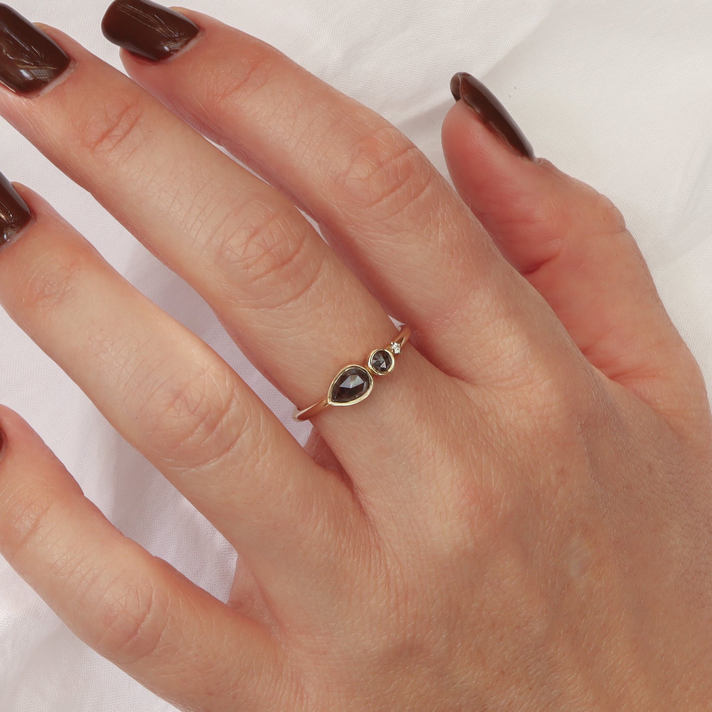 טבעת זהב עדינה עם שלושה יהלומים מדורגים על אצבע, המציגה את הפרופורציה המדויקת של העיצוב.