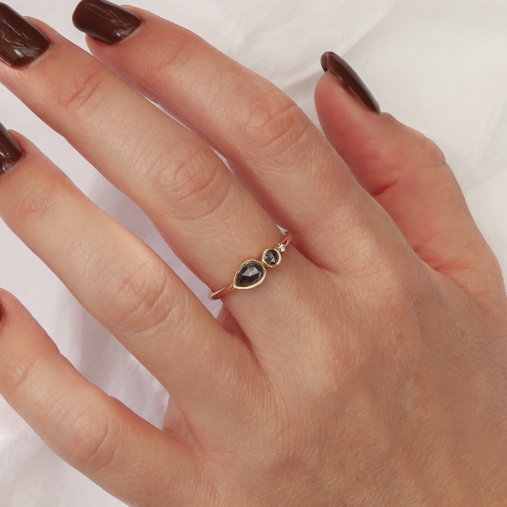 טבעת זהב עדינה עם שלושה יהלומים מדורגים על אצבע, המציגה את הפרופורציה המדויקת של העיצוב.