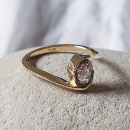 מבט מהצד על המבנה הגיאומטרי של הליפוף המדגיש את הנוכחות הויזואלית של הזהב סביב האבן.