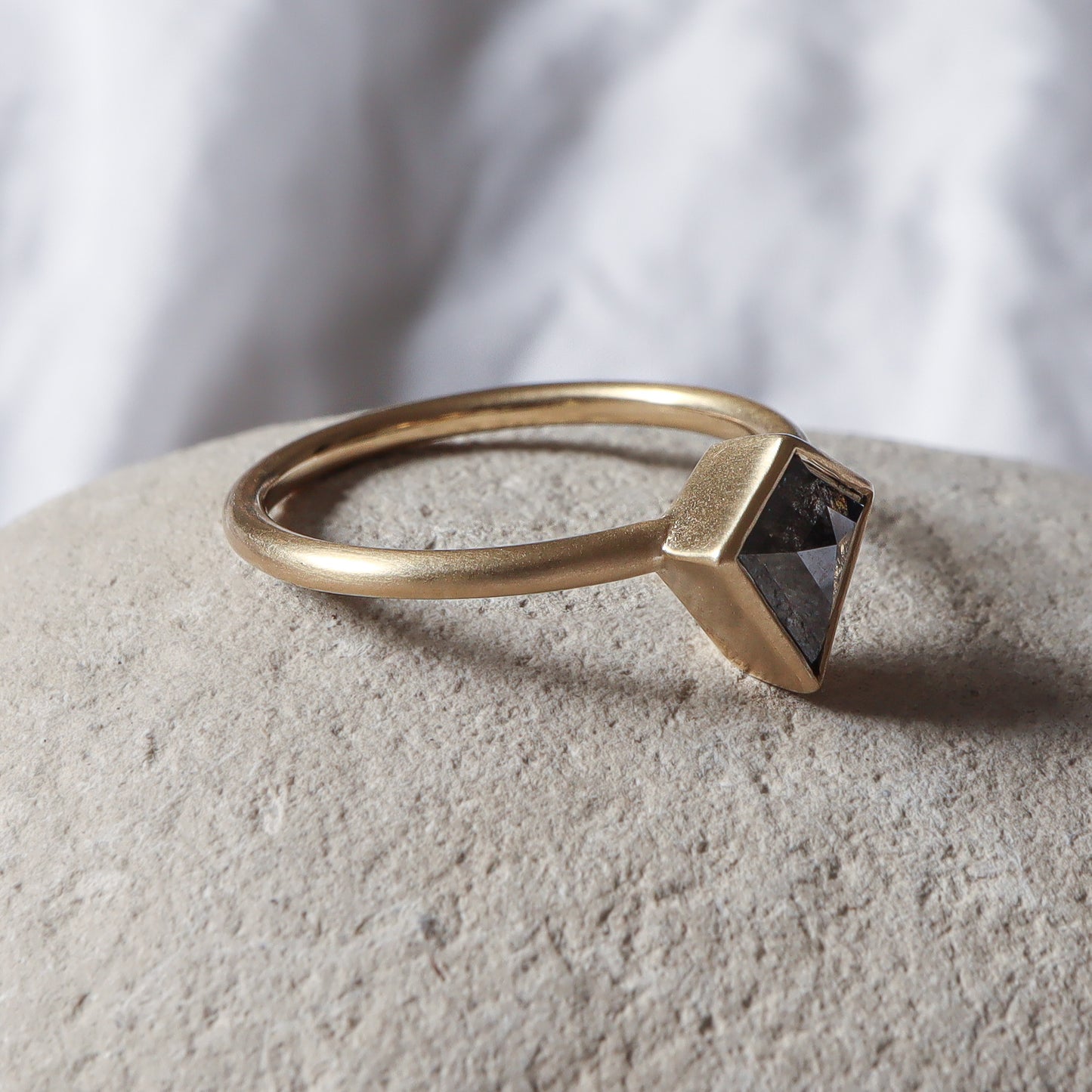 פרופיל צד של טבעת זהב בכימור מט משובצת יהלום אפור בחיתוך דלתון.