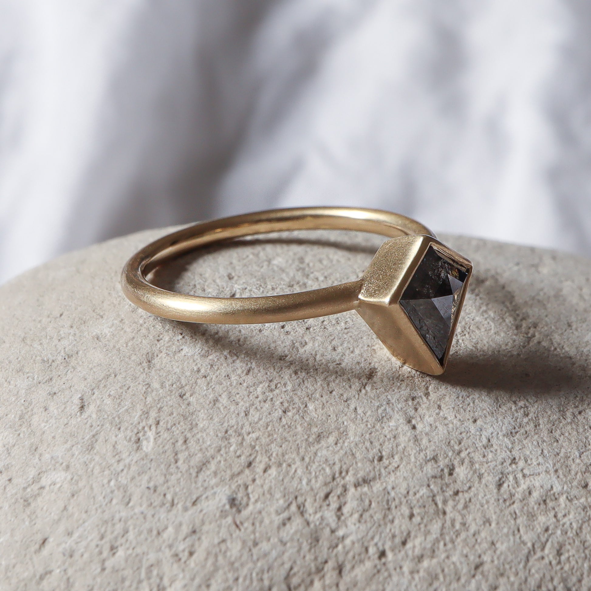 פרופיל צד של טבעת זהב בכימור מט משובצת יהלום אפור בחיתוך דלתון.