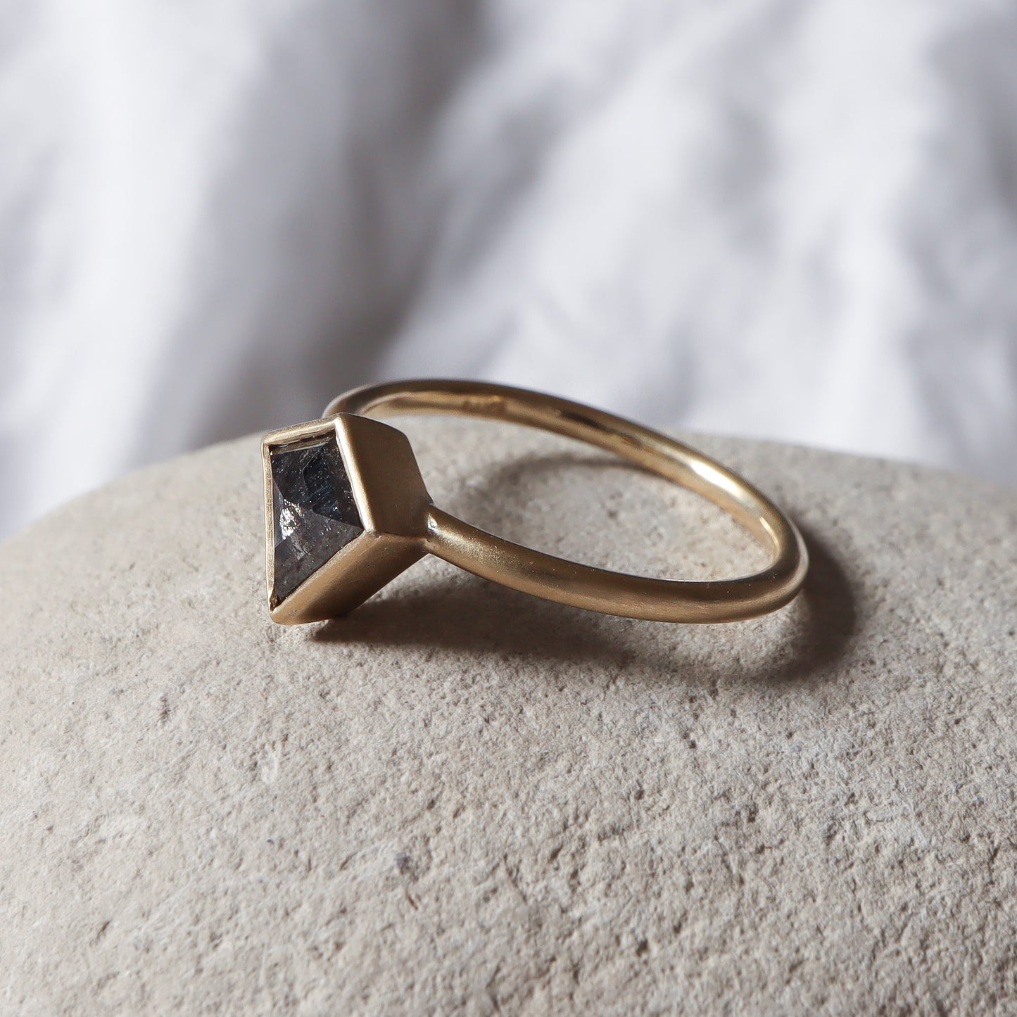 Profile angle of a salt pepper kite shape diamond set in a bezel ring with matte finish.