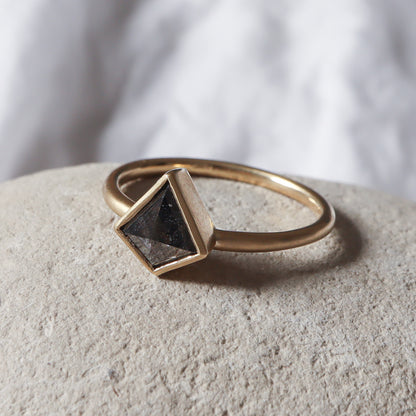 טבעת דלתון בגימור מט מונחת על אבן, המבליטה את המראה הגולמי והנקי של העיצוב.