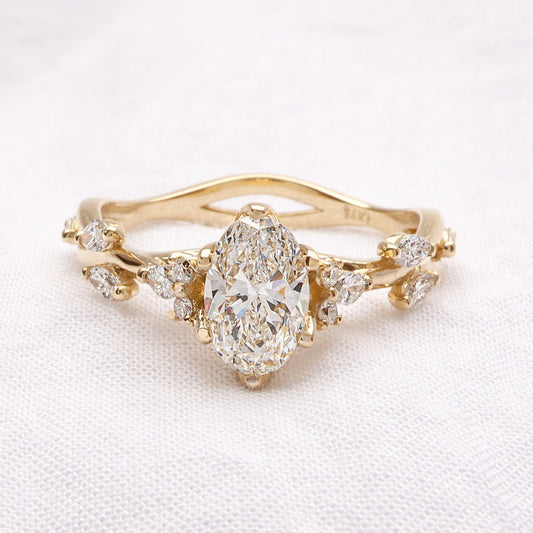 טבעת אירוסין זהב 14 קראט עם יהלום אובל מרכזי ויהלומי מרקיזה המדמים עלים בשיבוץ גיאומטרי.