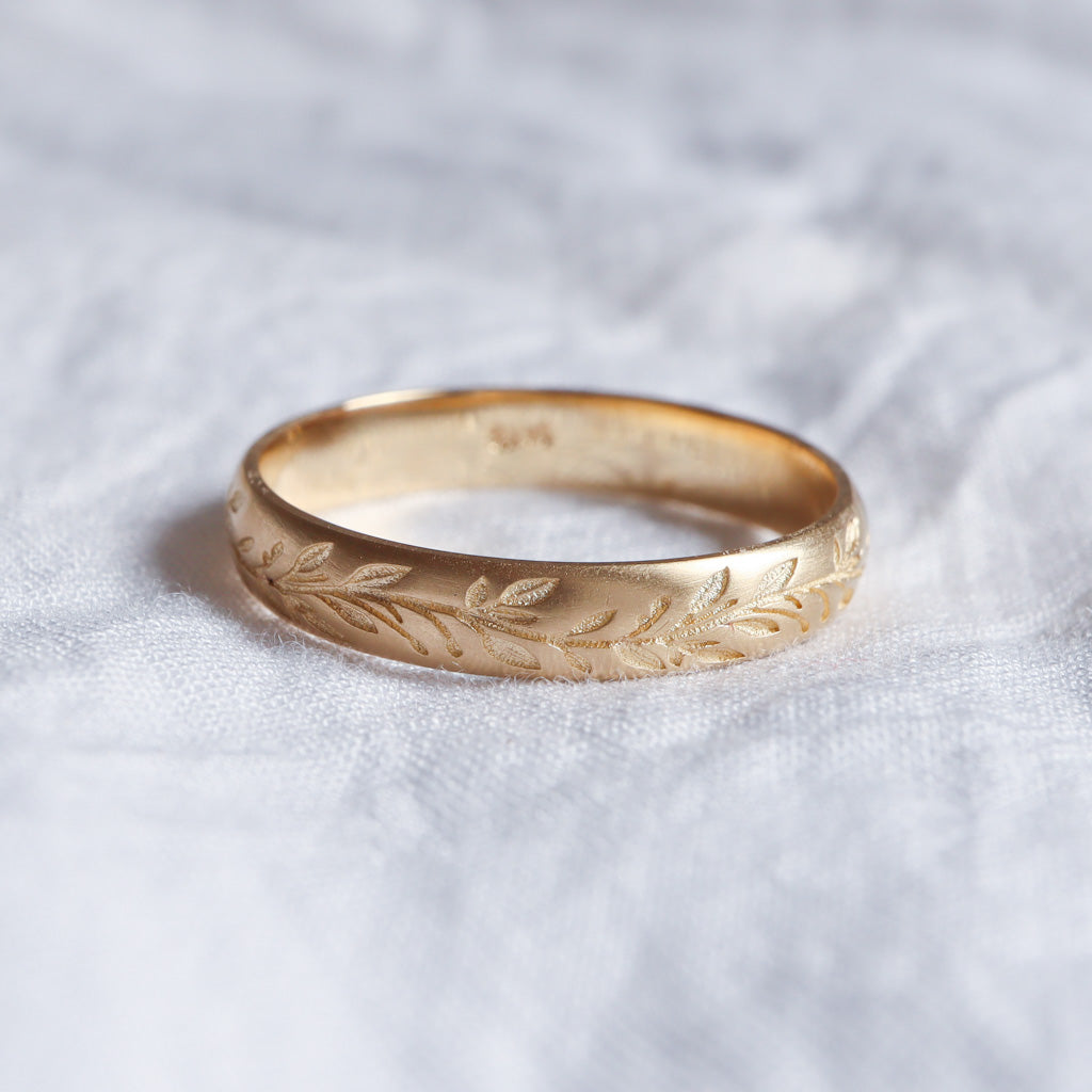 טבעת נישואים עדינה בזהב צהוב עם חריטות של עלים מיוחדים.