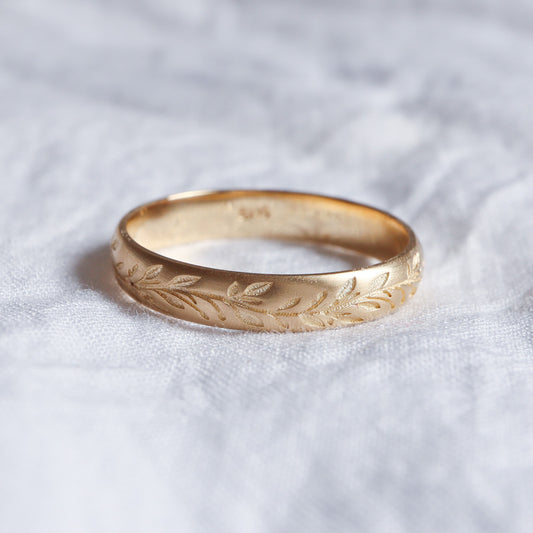 טבעת נישואים עדינה בזהב צהוב עם חריטות של עלים מיוחדים.