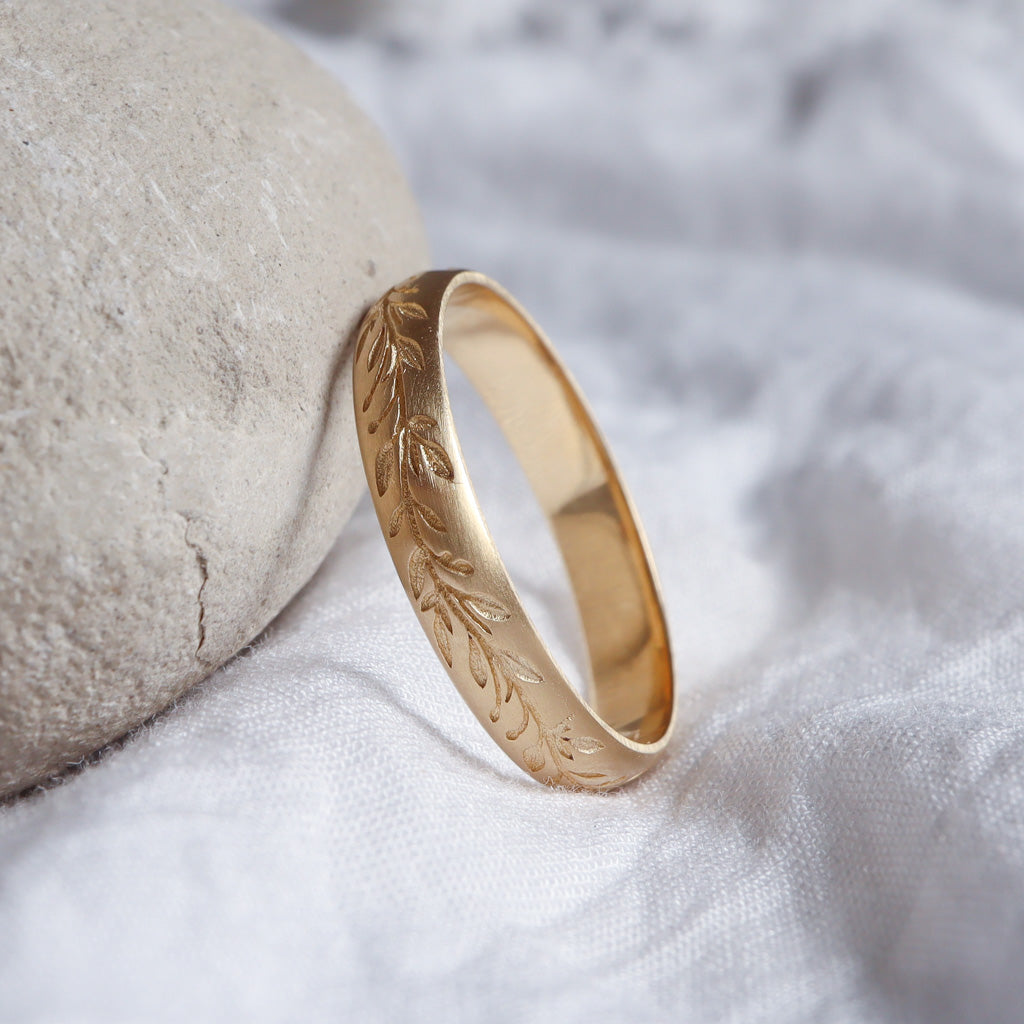 צילום צד של טבעת הנישואין המבליט את עובי הזהב והדיוק של חריטת העלים.
