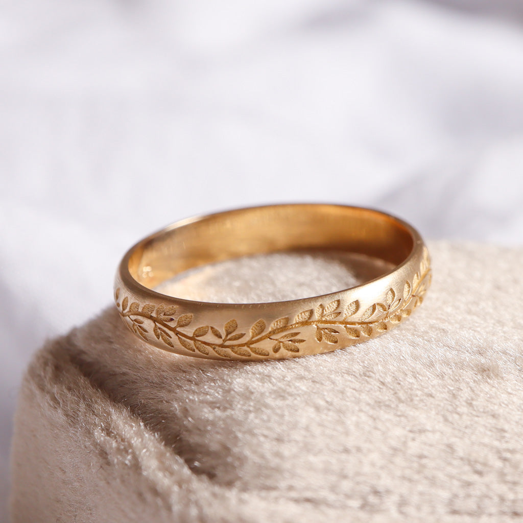 טבעת נישואים בזהב צהוב עם חריטות של עלים.