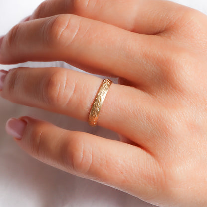 טבעת נישואין עלי דפנה על אצבע המציגה את השילוב בין המבנה הגיאומטרי למראה האורגני.