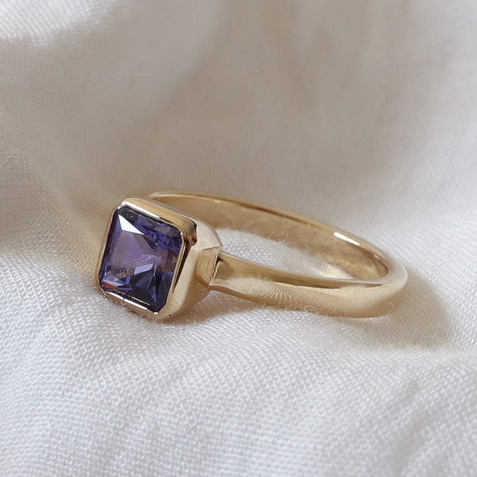 Gemstone gin featuring a natural amethyst in a gold bezel setting band.