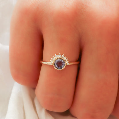 A close-up view of the lavender sapphire ring with a diamond crown on the finger, showing its refined presence.