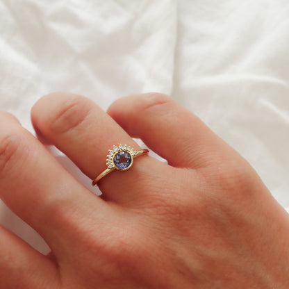 A lifestyle shot of the delicate gold sapphire ring on the hand, highlighting the soft purple hue of the gemstone.
