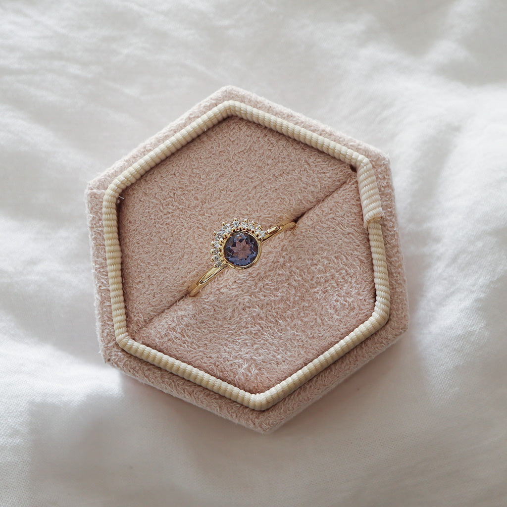 The lavender sapphire ring displayed inside a pink velvet jewelry box, emphasizing the contrast of the diamonds.