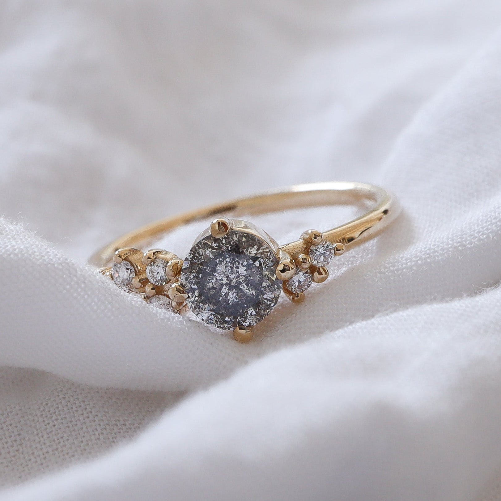 Gold cluster style ring featuring a salt and pepper diamonds accented with white clear diamonds.