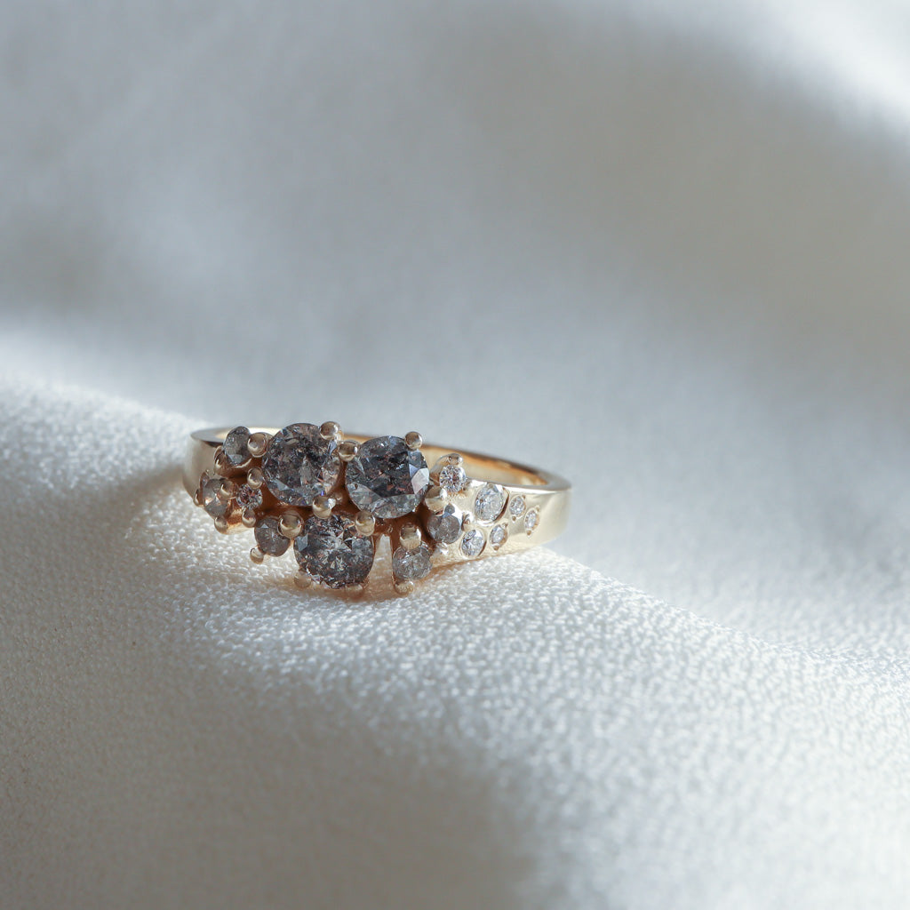 Side profile of a Salt & Pepper Diamond cluster ring in 14K yellow gold on white fabric – Dina Jewelry