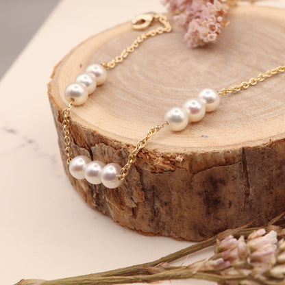 Gold three pearl station bracelet elegantly displayed on a wooden display