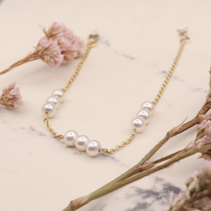 Gold three pearl station bracelet elegantly displayed on a marble slab