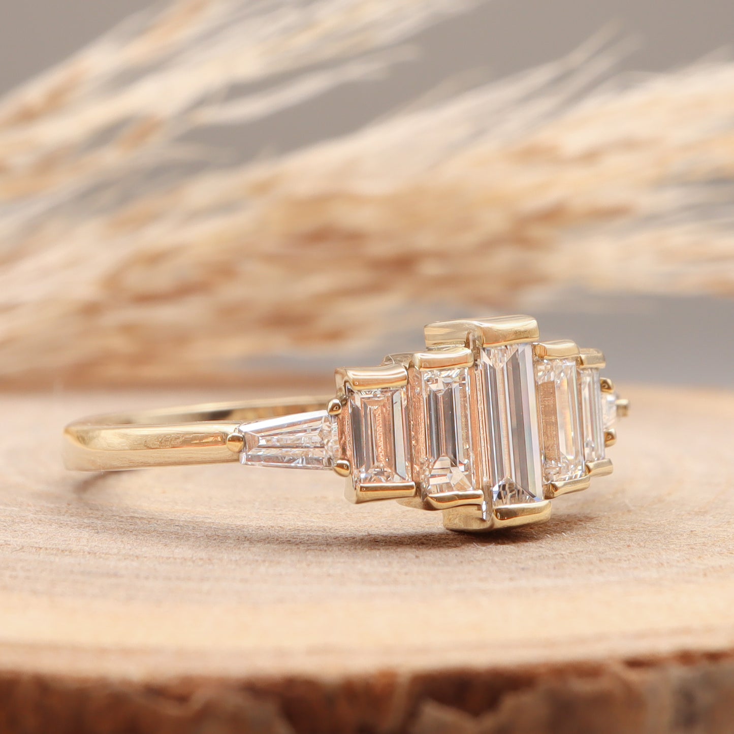 Diamond Baguette Gold Ring with Bezel-Set Vertical Step Design on wooden display, profile view.