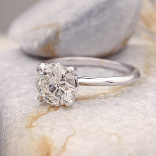 Solitaire Ring - Round Cut Diamond in White Gold, resting on a grey stone.