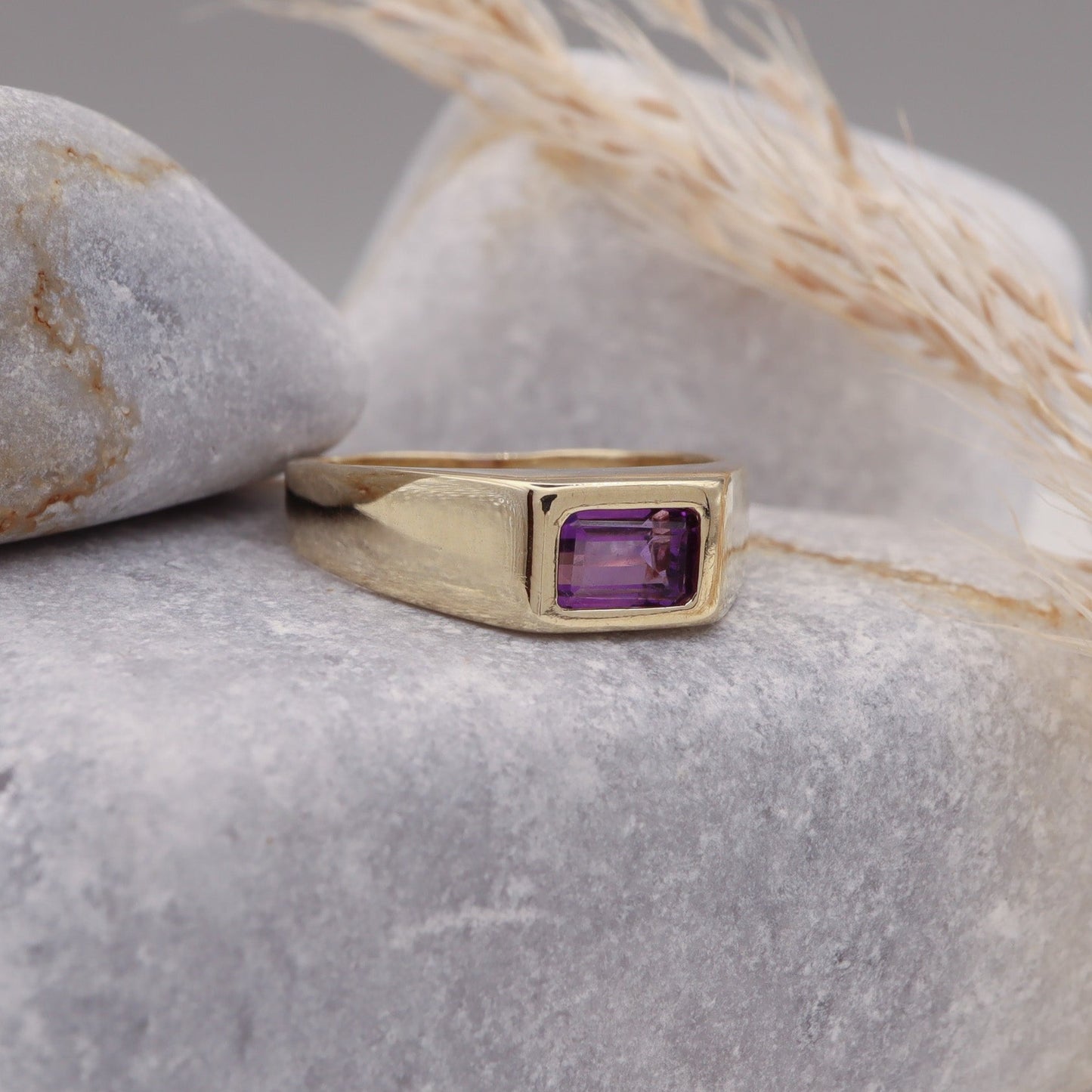 Profile view of the Natural Amethyst Square Signet Ring in Solid Gold displayed on a grey stone.