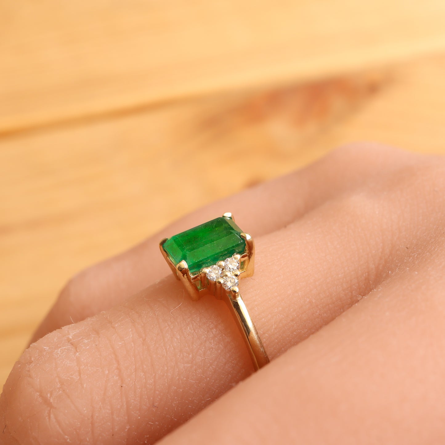 Side view of an emerald engagement ring worn on a woman's finger.