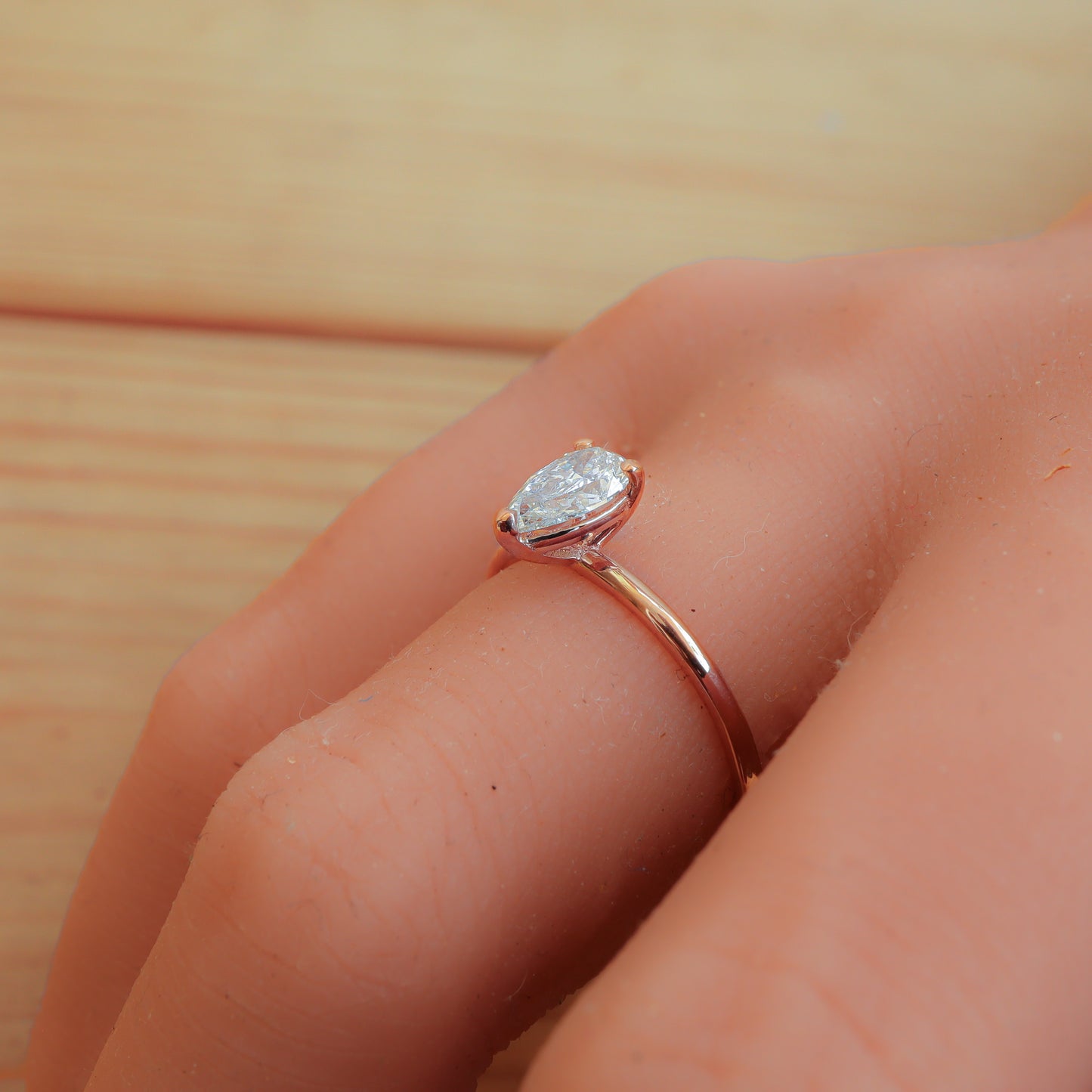 Profile View of 3 Prong Solitaire Pear Diamond Ring in Rose Gold on Woman's hand.