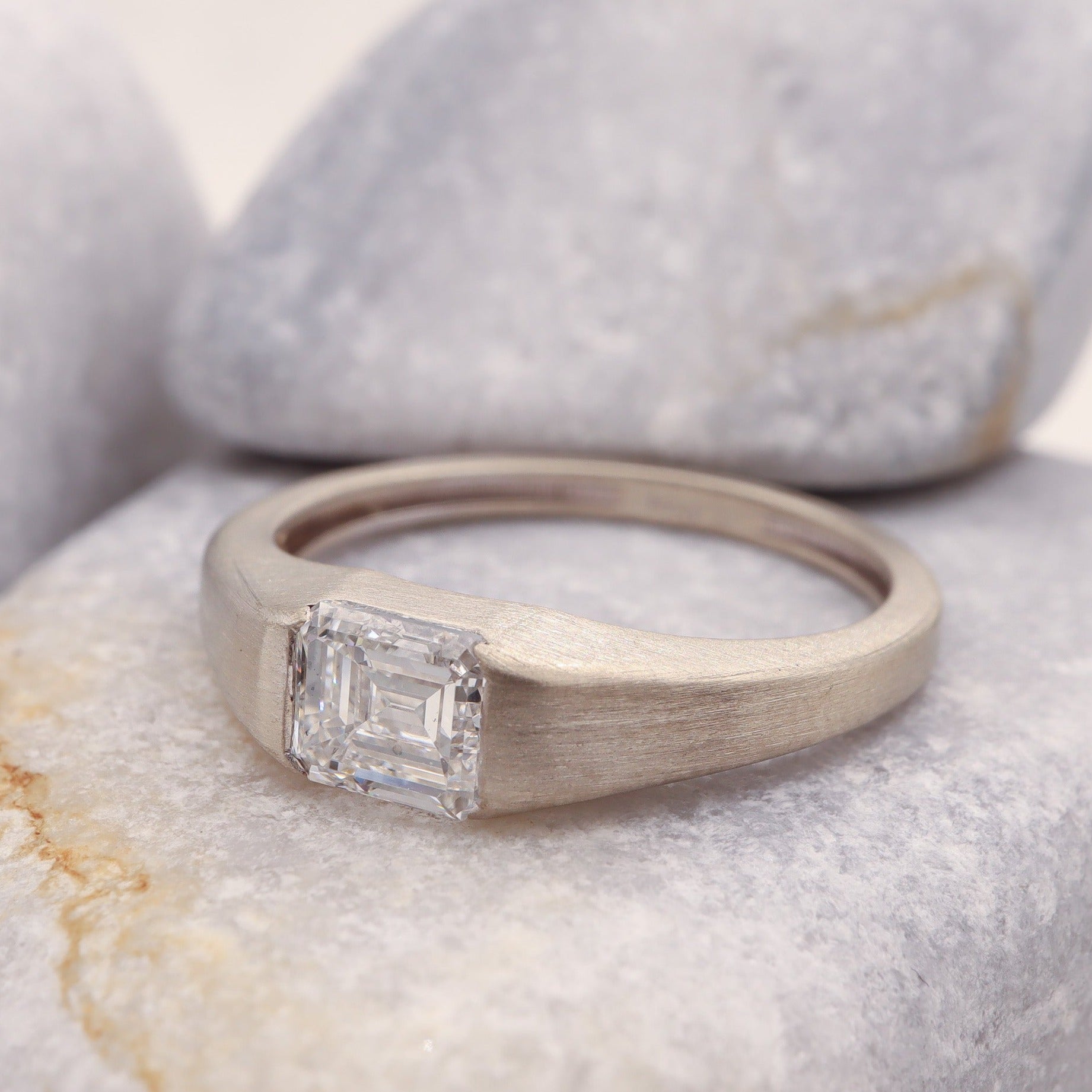 Profile view of our rustic white gold tension ring featuring a square emerald cut diamond.